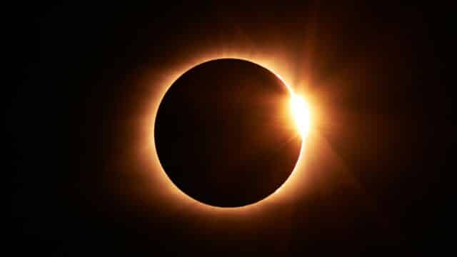 total eclipse of the sun is a ring of orange light that is dark in the center in a dark sky